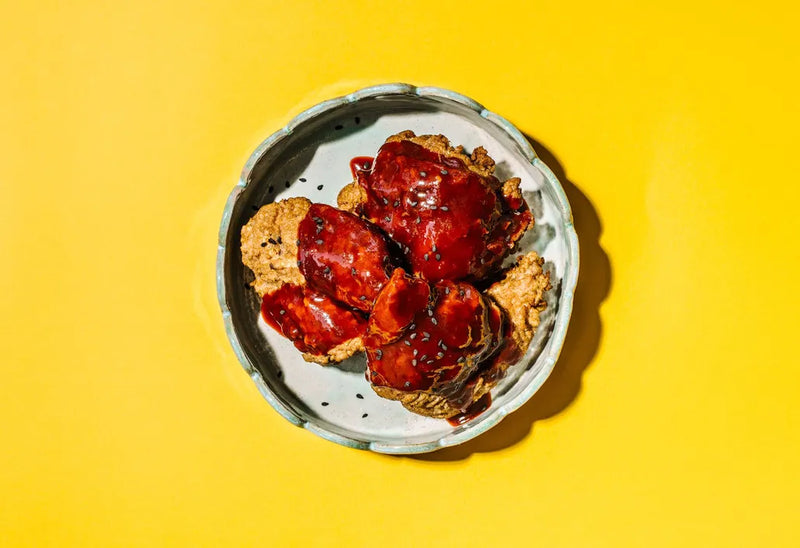 Biscuits with red jam on a white plate against a yellow background