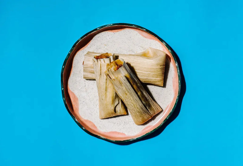 Tamales on a decorative plate with a blue background