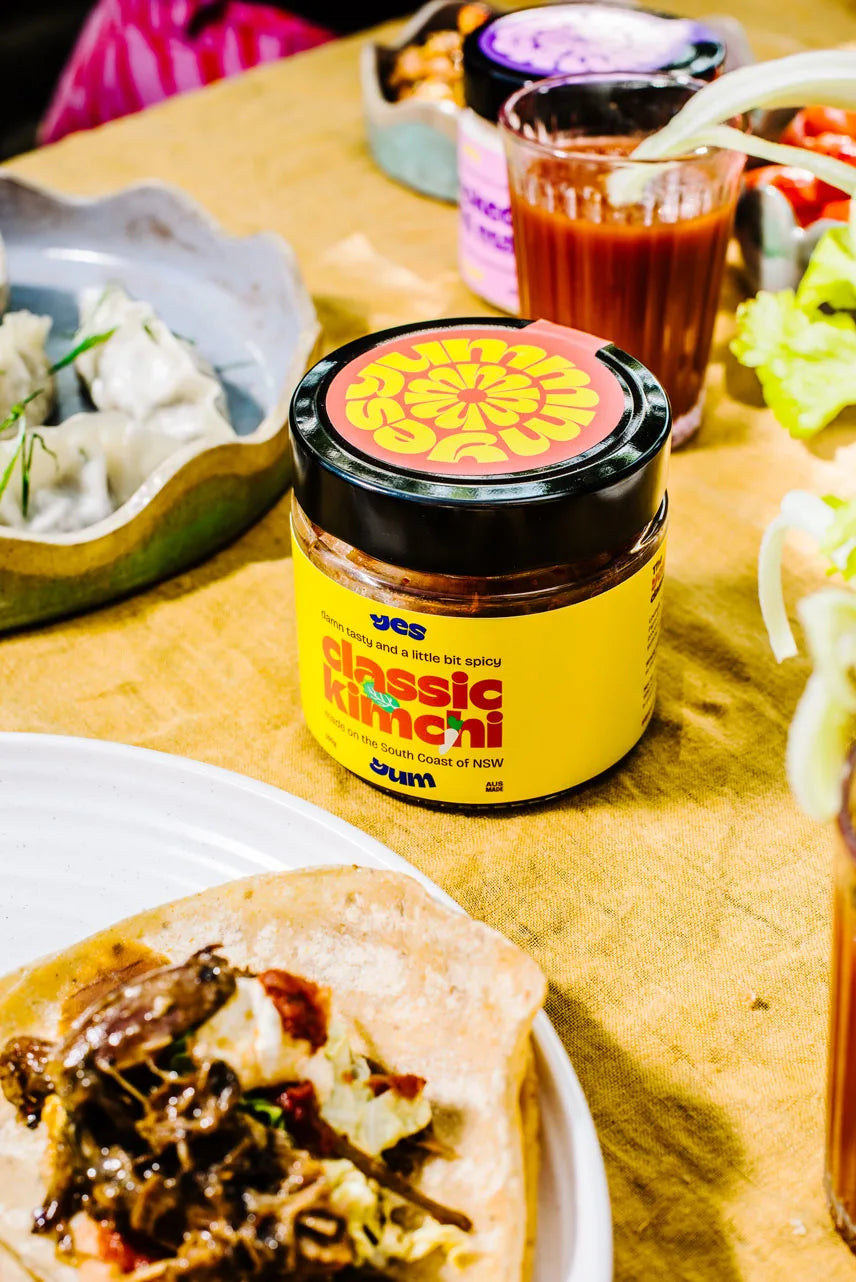 Jar of classic kimchi on a table with food items