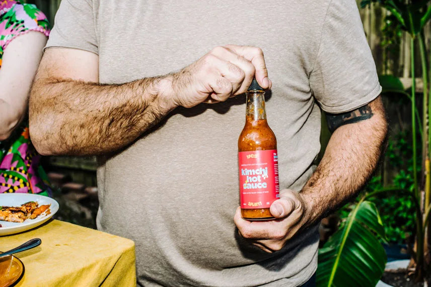 Person holding a bottle of hot sauce outdoors
