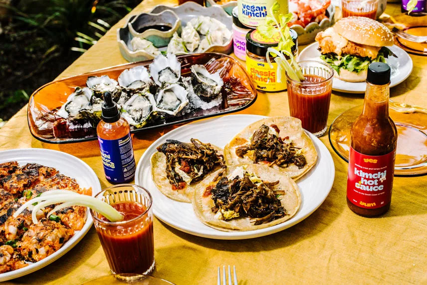 Table with various food items, including tacos and drinks, on a wooden surface.
