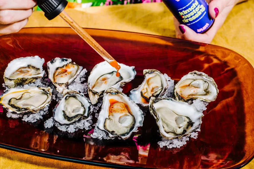 Oysters on a bed of ice with a bottle of sauce in the background