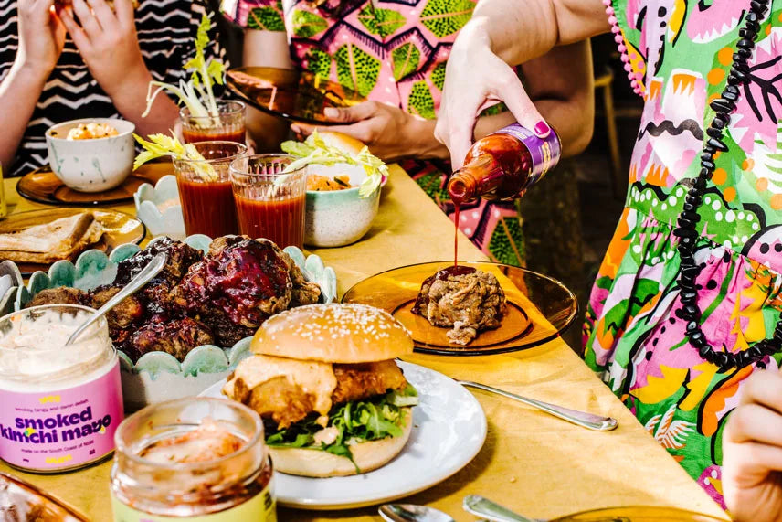 People enjoying a meal with burgers, fries, and drinks at a table.