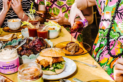 People enjoying a meal with burgers, fries, and drinks at a table.