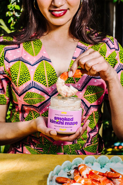 Woman holding a container of smoked mirror mussels with a colorful patterned shirt.