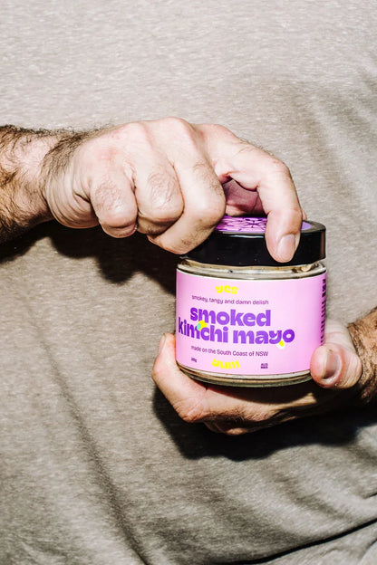 Person holding a jar of 'smoked kimchi mayo' with a pink label.