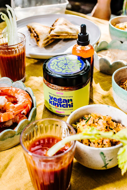 Table with food and a bottle of 'vegan kimchi' on a wooden surface